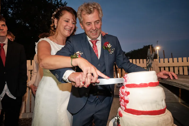 Saskia en Pim snijden de taart aan met rode bloemen