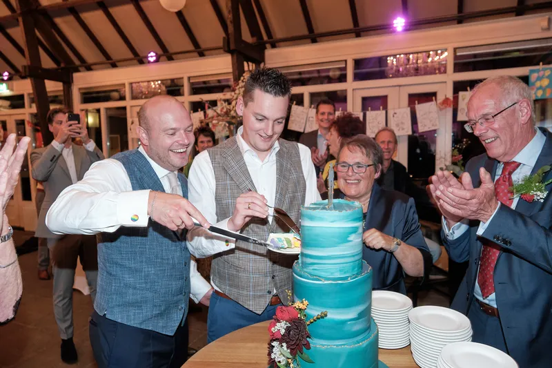 Mathijs en Jeroen snijden de taart aan, de gasten klappen