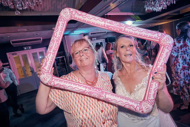 Ingeborg en een gast poseren met een roze fotolijst