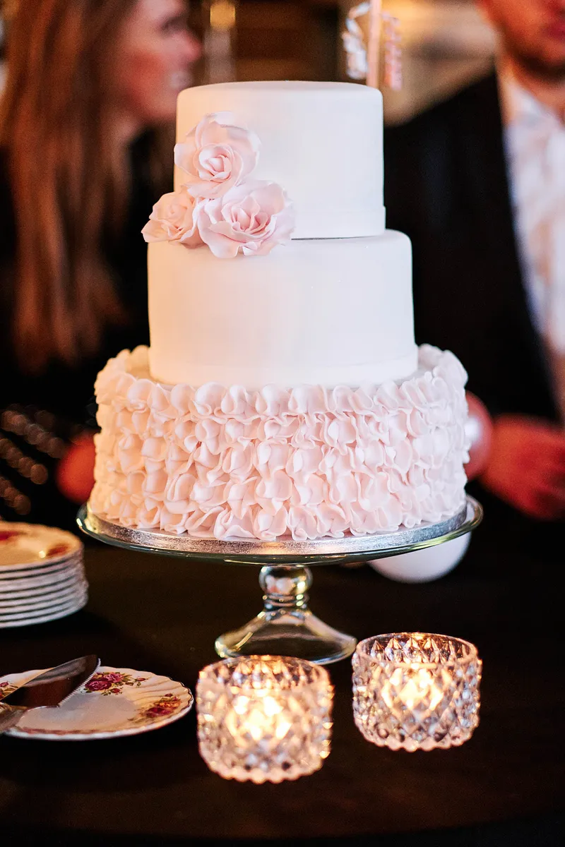 De bruidstaart met roze rozen en kaarsjes