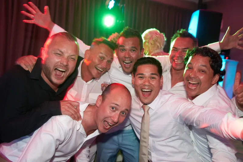 Een groep mannen in overhemd lacht op de dansvloer