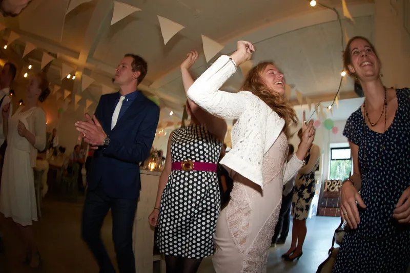 Gasten klappen en dansen in de zaal met slingers
