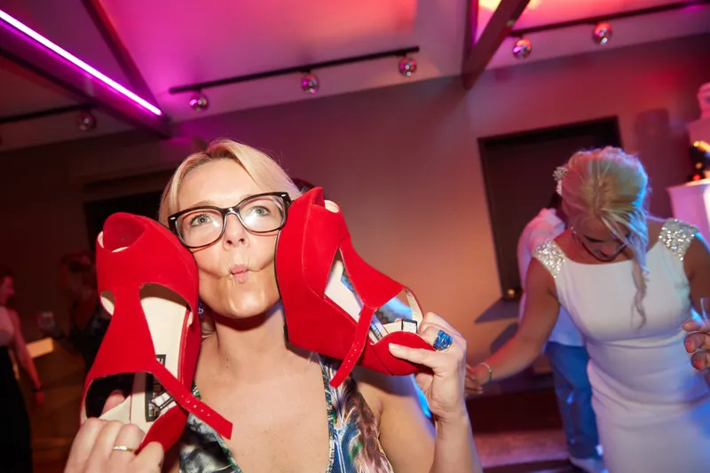 Een gast houdt rode schoenen omhoog