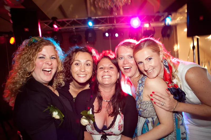 Vriendinnen lachen dicht tegen elkaar in het roze licht