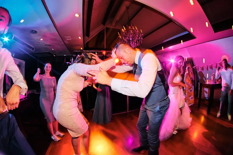 Twee gasten dansen dicht tegen elkaar in roze licht