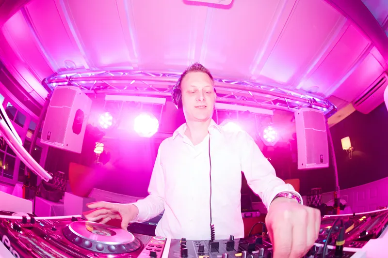 DJ Ferry G achter de draaitafels in roze licht