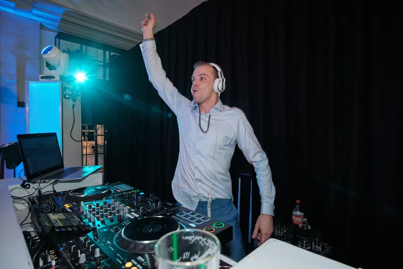 De dj steekt zijn arm in de lucht achter de draaitafels
