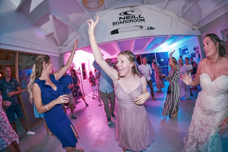 Gasten dansen met hun armen in de lucht in het roze licht