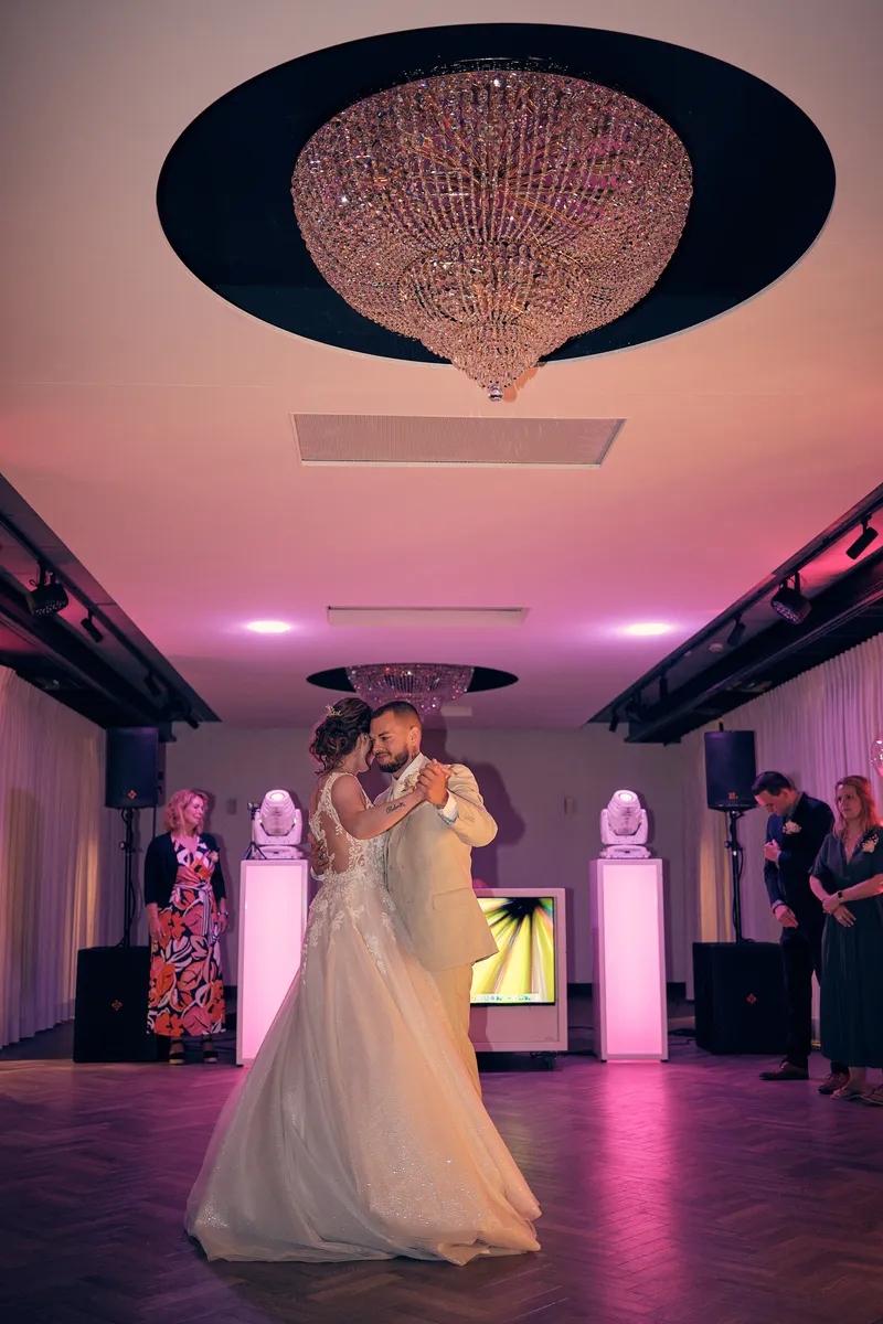 Wendy en Robin dansen onder de kroonluchter in roze licht