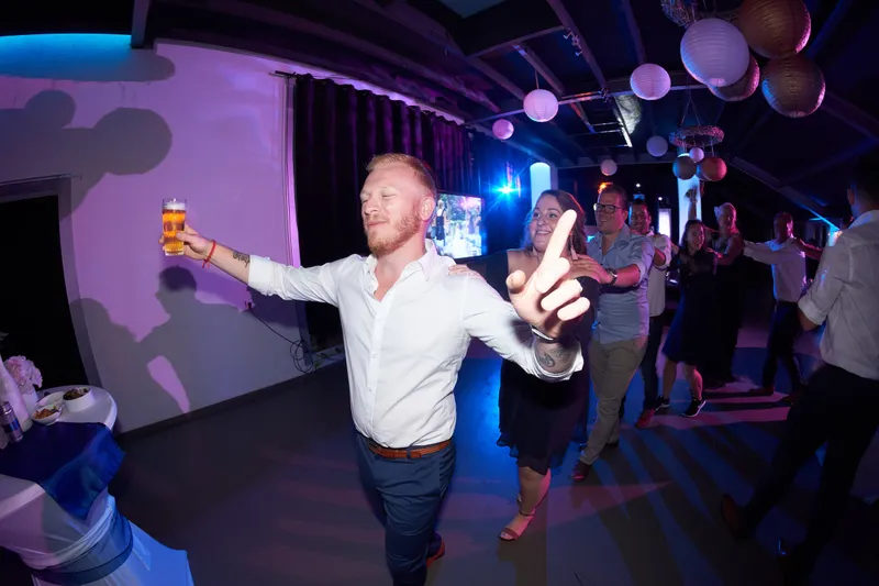 Een gast met een biertje danst de zaal in