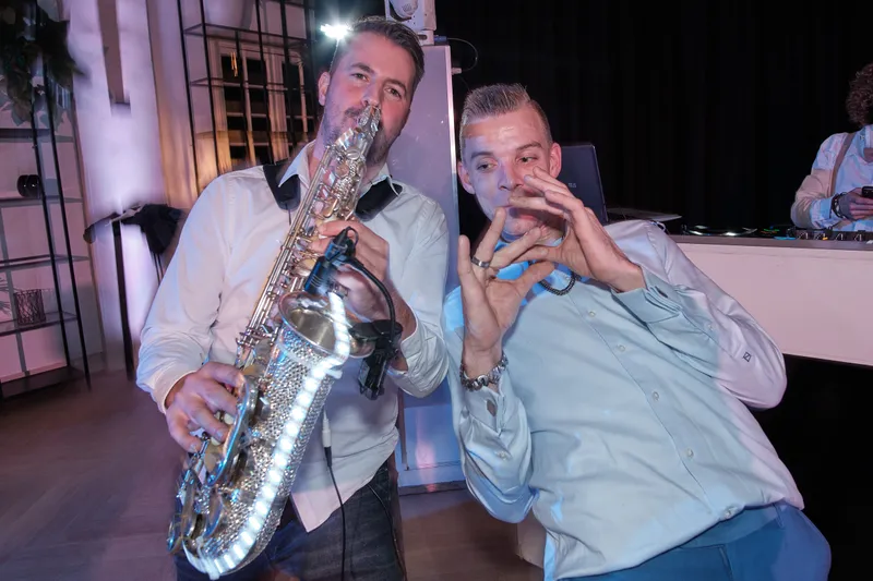De saxofonist speelt naast een juichende gast