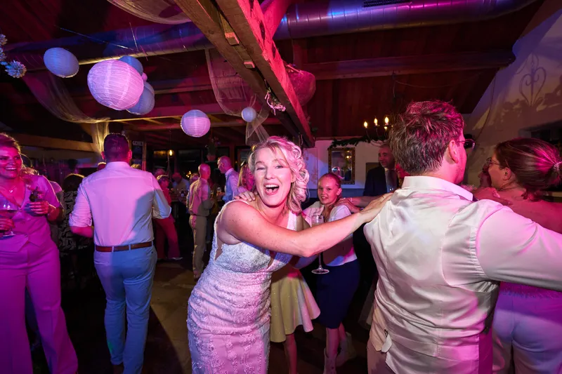 De bruid danst lachend met een gast