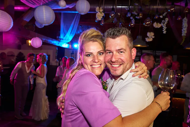 Twee gasten omhelzen elkaar lachend op de dansvloer