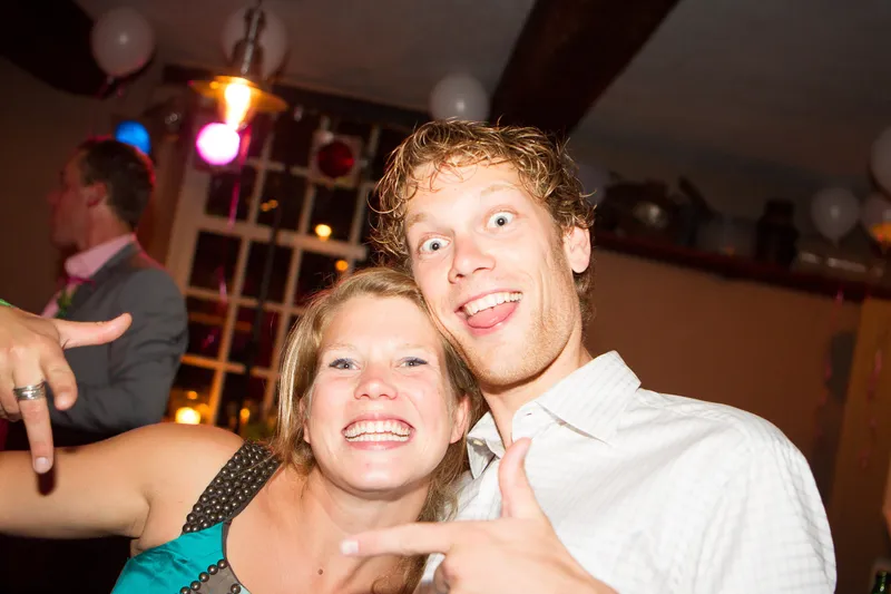 Twee gasten lachen naar de camera op de dansvloer