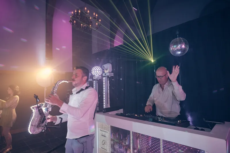 De saxofonist en de dj met lasers boven de zaal