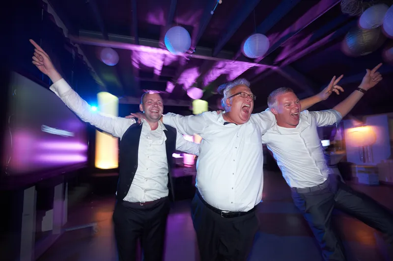 Drie mannen dansen met hun armen wijd