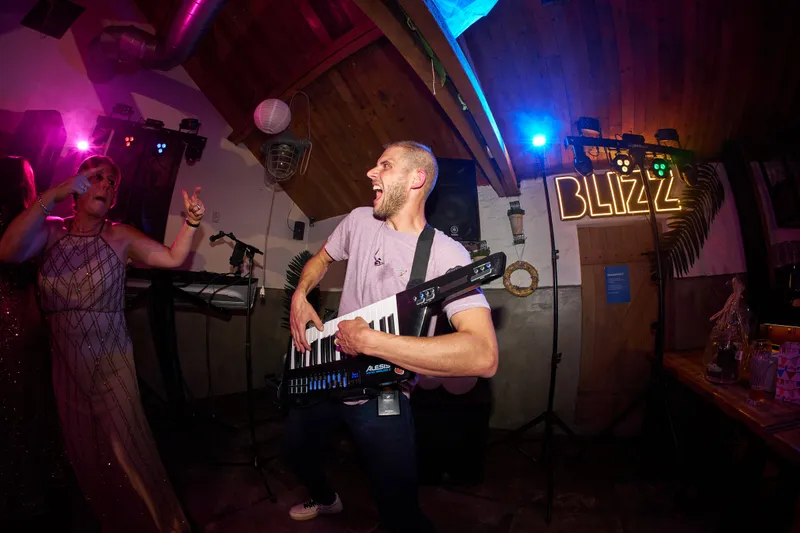 De gitarist op het podium, met het grote neonbord van Blizz