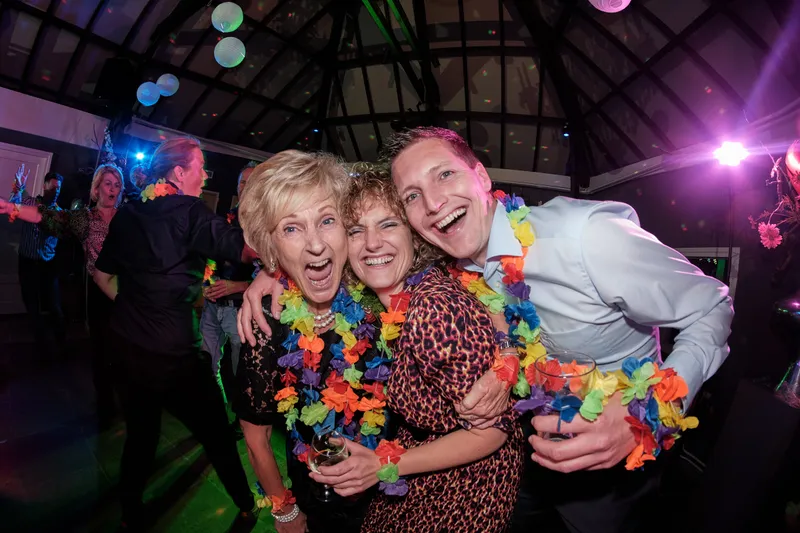 Een vriendin omhelst de twee, allemaal met bloemenkransen