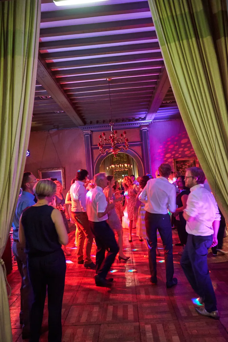 De zaal met de groene gordijnen vol dansende gasten