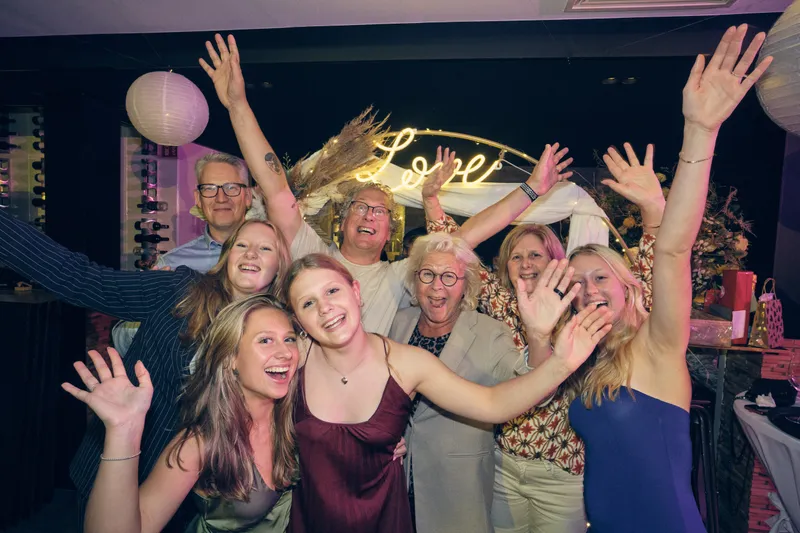 Een groep gasten juicht met de armen omhoog