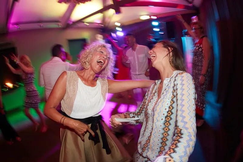 Twee vriendinnen dansen in roze en blauw licht