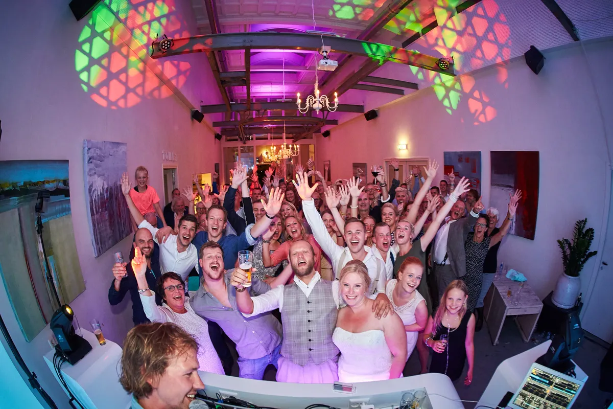 Gasten steken hun handen omhoog onder de discobal