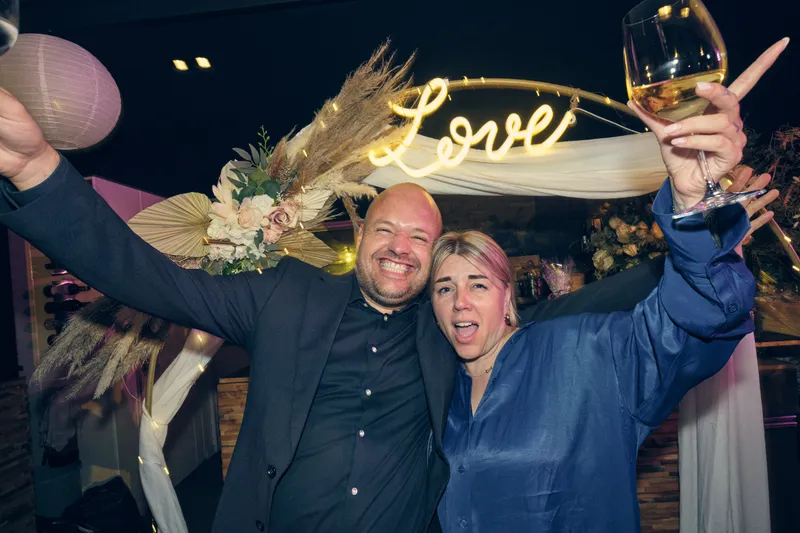 Twee gasten proosten onder de ‘Love’-boog