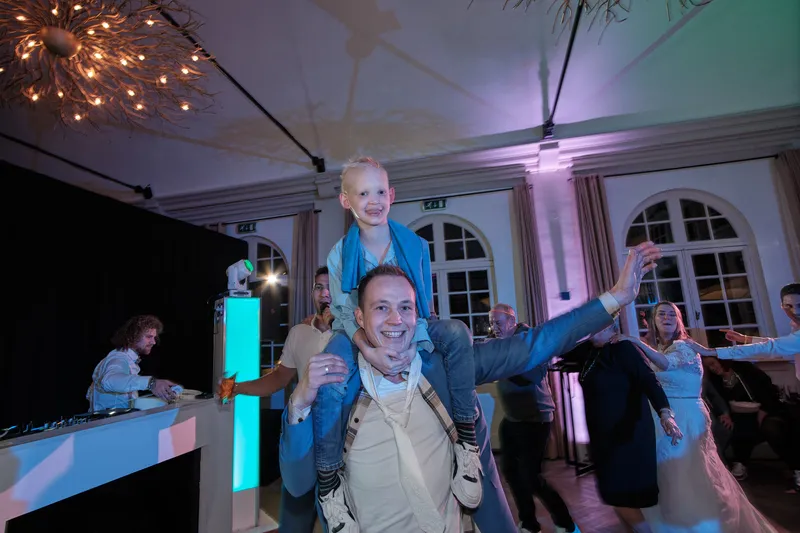 Een gast op de schouders van een andere gast op de dansvloer