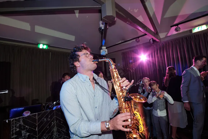De saxofonist speelt bij de dj