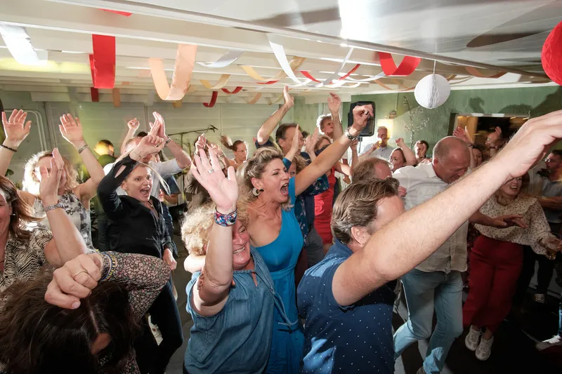 Gasten met opgestoken handen in de zaal