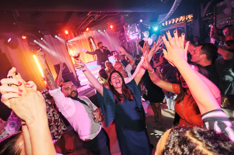 De gasten dansen en juichen onder roze licht