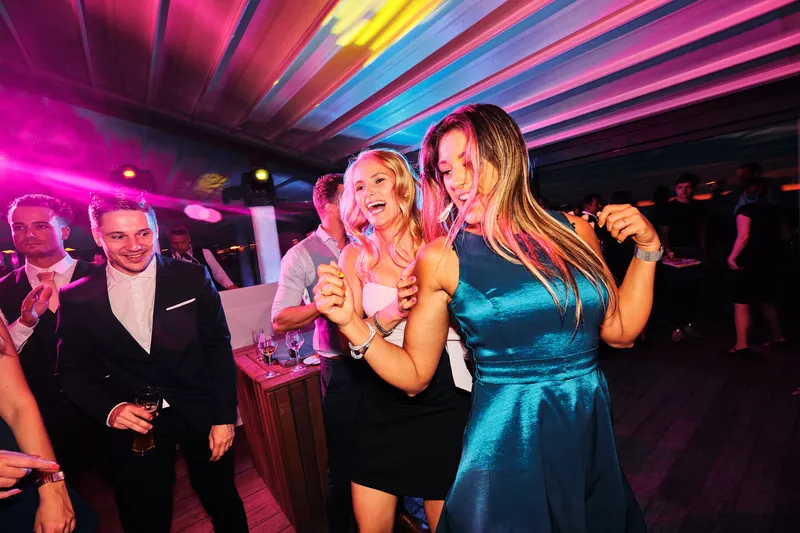 Gasten dansen in roze en blauw licht