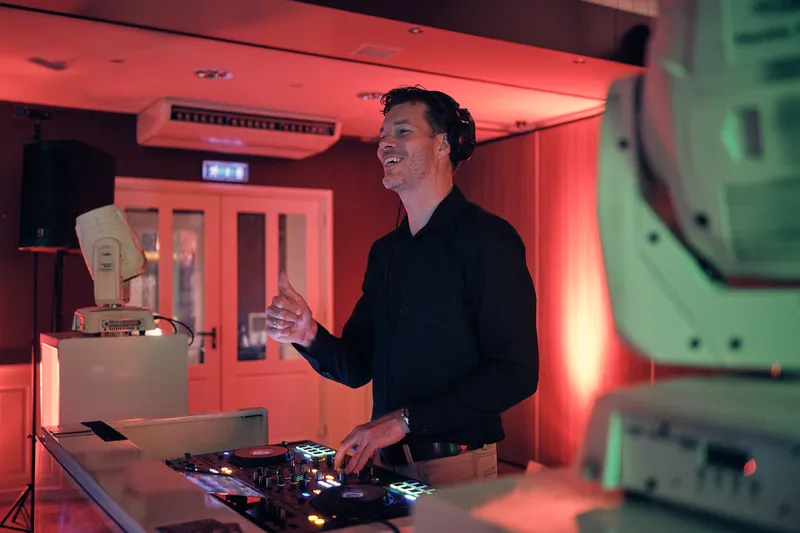De dj achter de draaitafels in rood licht