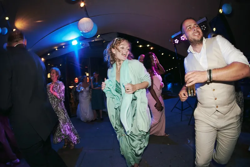Een vrouw in een groene jurk danst tussen de gasten, scherp in beeld