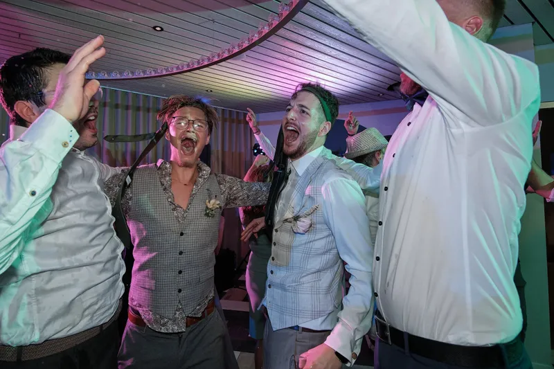 Drie mannen zingen uit volle borst mee op de dansvloer
