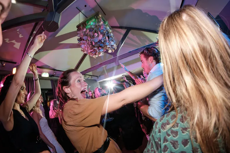 Gasten juichen met de armen omhoog onder een discobal