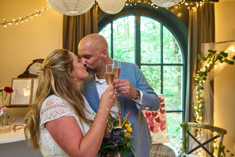Annemarie en Jan kussen elkaar met een glas bubbels in de hand