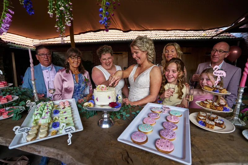 Familie en de bruiden achter de sweet table met donuts, koekjes en de taart