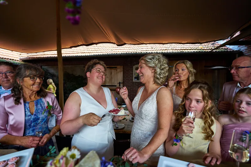 De bruiden en familie eten taart in de tent