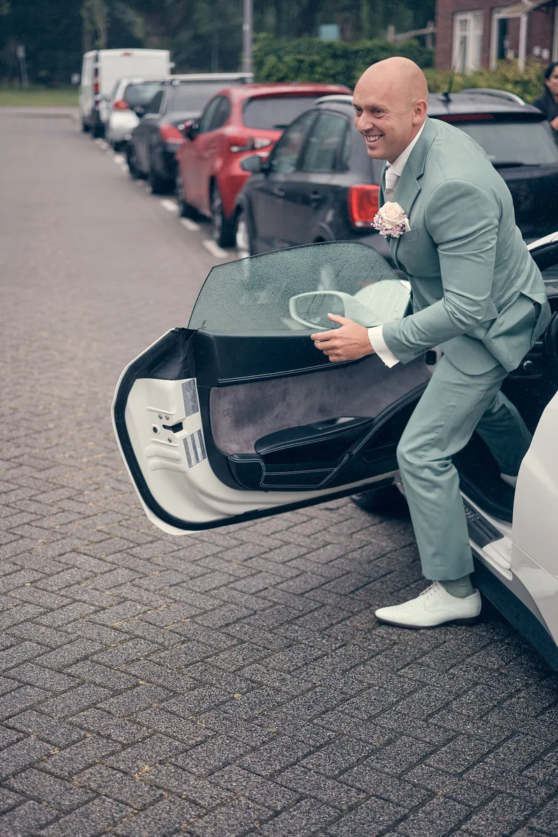 Dennis doet het portier van de Ferrari open