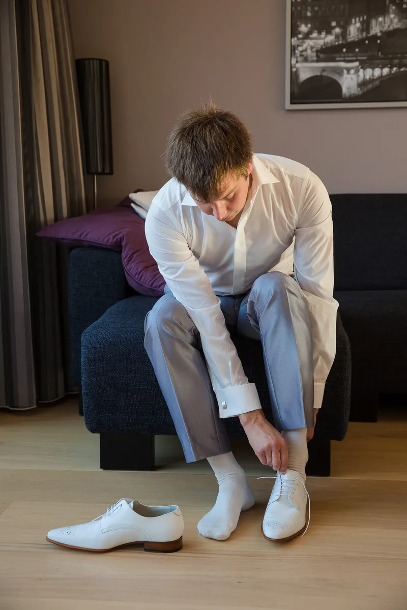 Ferry trekt op de bank zijn witte schoenen aan