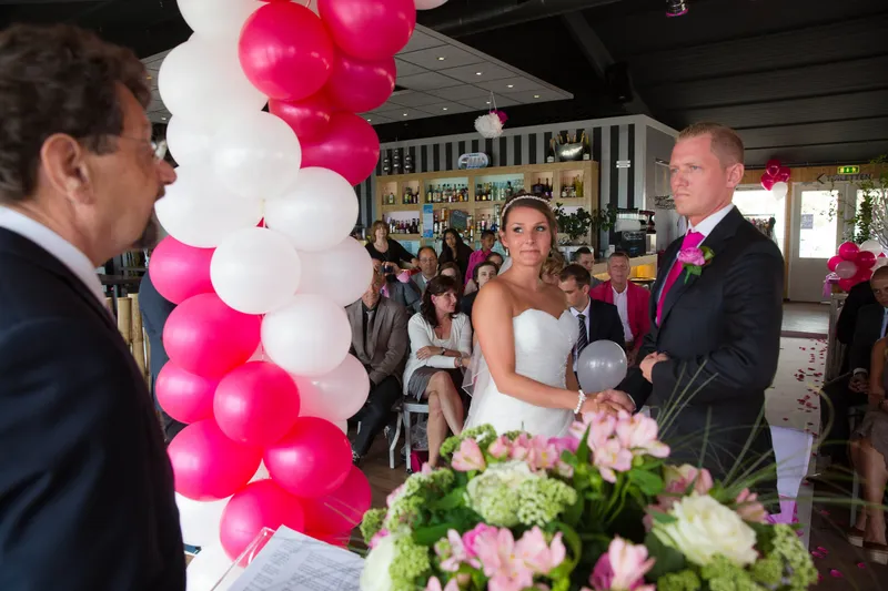 Michelle en Sven tijdens de ceremonie, tussen roze en witte ballonnen