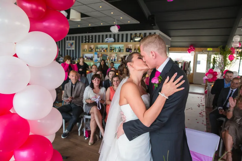 De kus na het jawoord, onder de ballonnenboog