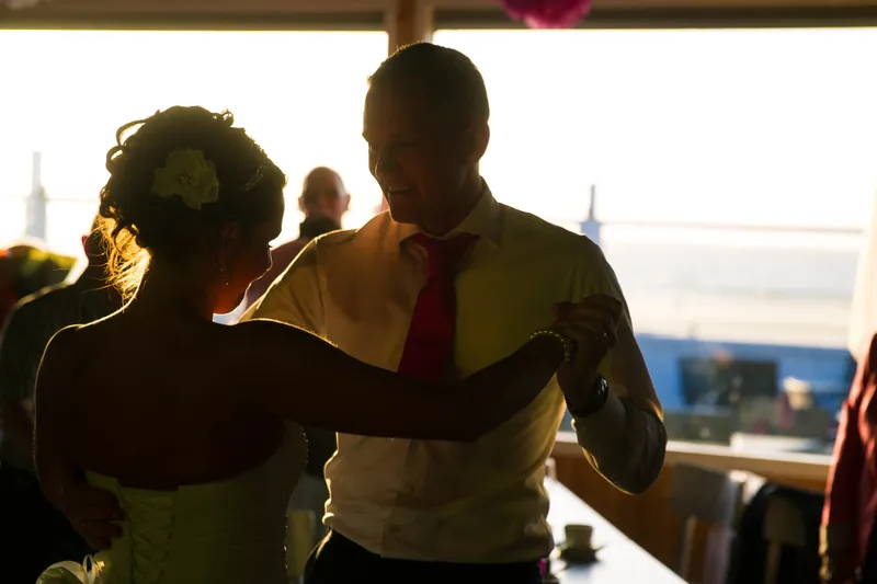 Michelle en Sven dansen in silhouet voor de ramen met uitzicht op zee