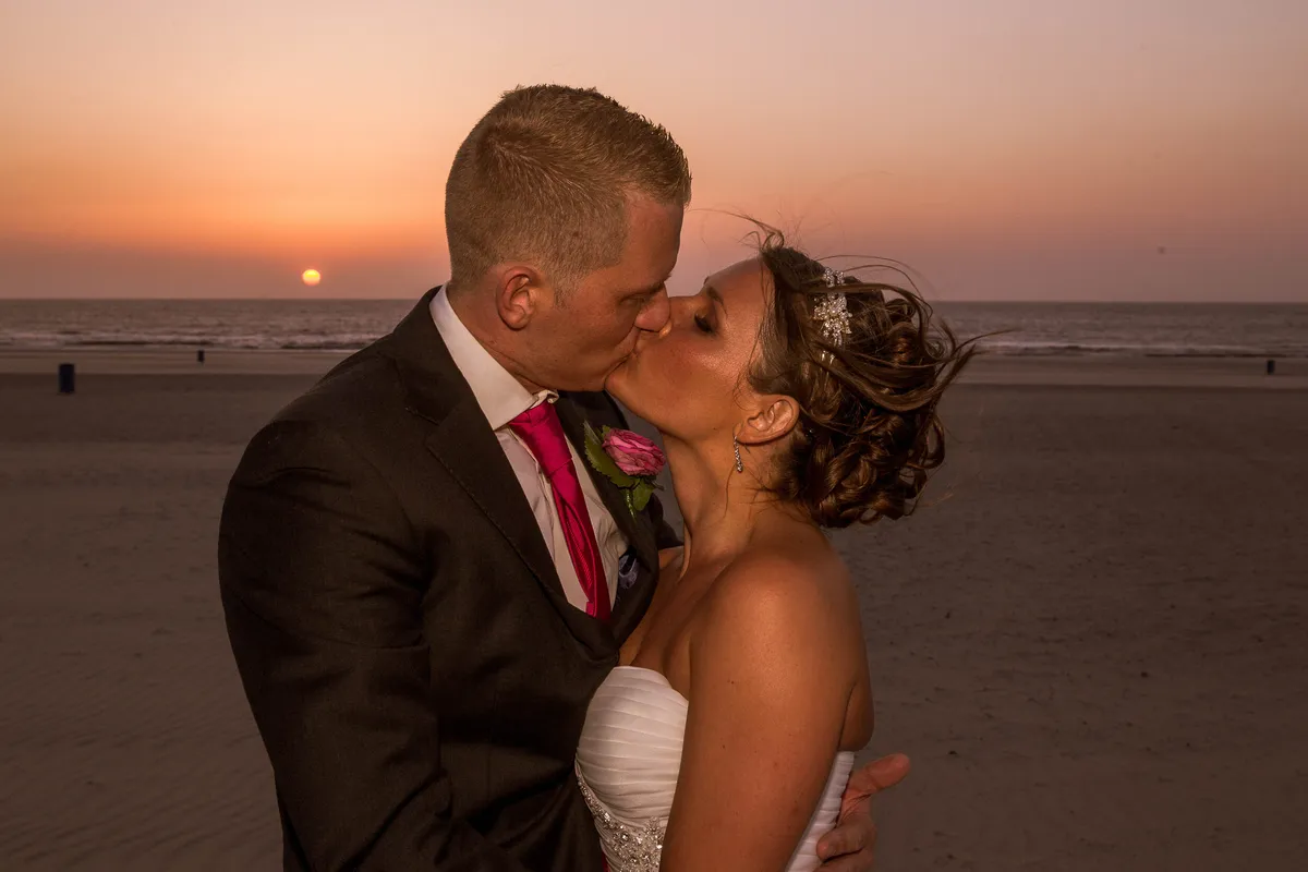 Michelle en Sven kussen op het strand bij zonsondergang