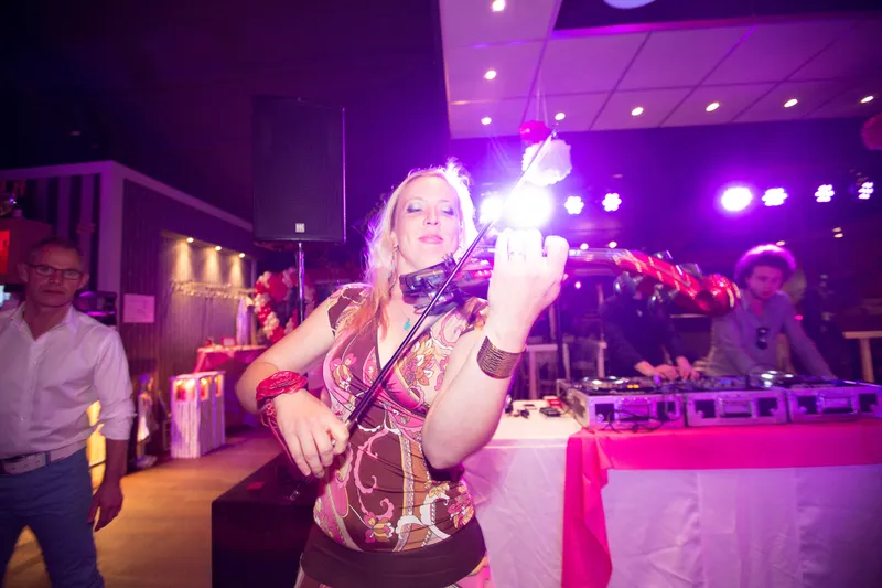 Een violiste speelt op het feest in paars licht