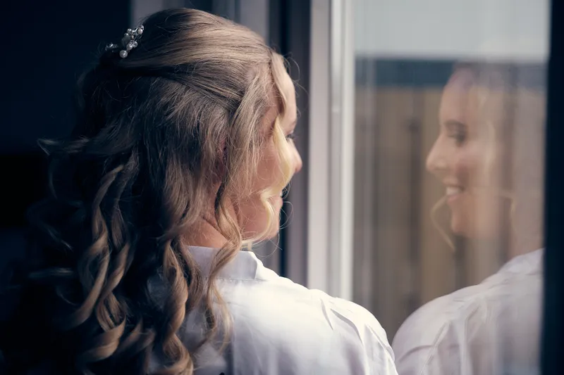 Kim kijkt uit het raam, haar spiegelbeeld in het glas