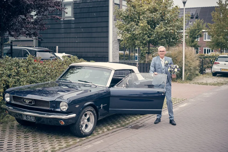 Herre wacht naast de donkerblauwe Mustang-cabrio
