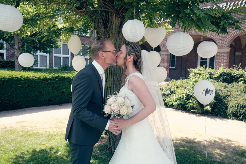 Mike en Ilja kussen elkaar onder de boom met witte lampionnen