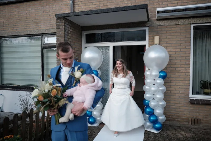 Gerrold met hun dochter op de arm, Wendy in de deuropening tussen de ballonnen